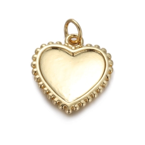 Detailed view of heart-shaped gold pendant with beaded edge and polished metal finish