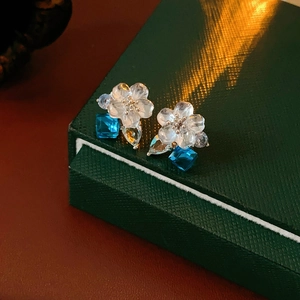 Macro view of floral stud earring with blue square crystal and teardrop gemstone detail