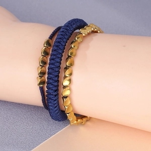 Handmade woven dark blue rope bracelet set with irregular gold beads on wrist