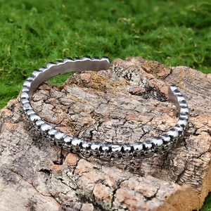 Macro shot of punk style skull open bangle on textured tree bark with moss background