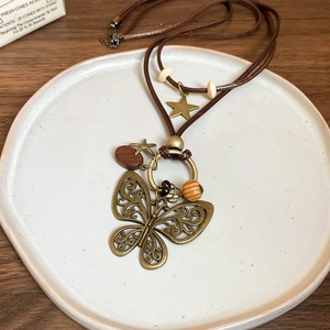 Detail of vintage wooden bead necklace with a large brass butterfly pendant on wax cord