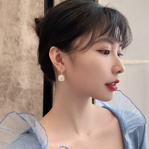Elegant gold square halo drop earrings with pavé crystals on a model for a chic look