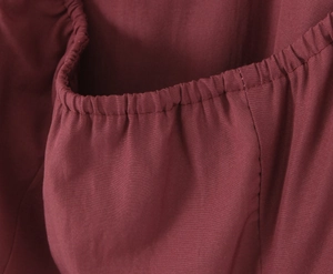 Close-up of dark red fabric showing elastic pleats and high-quality stitching details