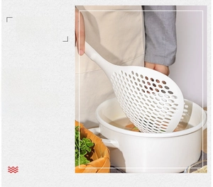 Detail of a large white kitchen slotted spoon filtering noodles over a boiling pot