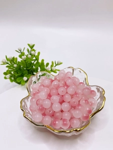 Macro shot of 8mm pink gradient glass beads in a gold-rimmed decorative bowl for DIY jewelry