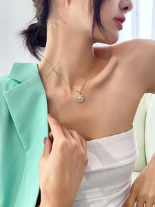 Detail of gold sunflower pendant necklace with zircons worn by model in green blazer