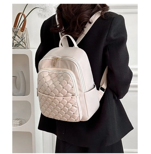Dettaglio dello zaino beige trapuntato con borchie dorate e spalline regolabili