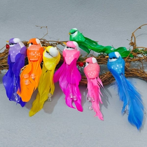 Colorful artificial birds with feather wings and beads resting on dry tree branches