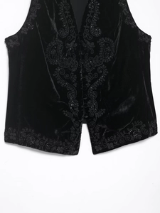 Macro view of velvet vest featuring ethnic paisley embroidery and beaded details