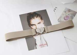 Détail de ceinture élastique beige avec une boucle cœur en métal argenté sur magazine