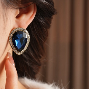 Gros plan d'un mannequin portant des boucles d'oreilles de luxe avec gemme bleue et cristaux