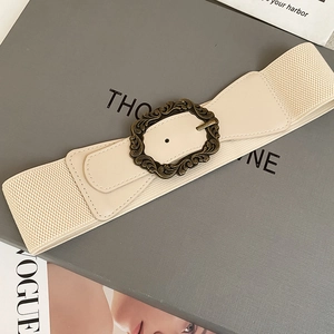 Détail de ceinture élastique beige avec boucle en bronze vintage sur un magazine