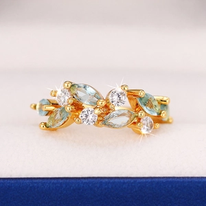 Macro shot of leaf-shaped gold ring featuring blue marquise gems and white zircons