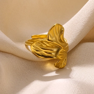 Detail of golden adjustable leaf ring showing delicate veins on a cream fabric background