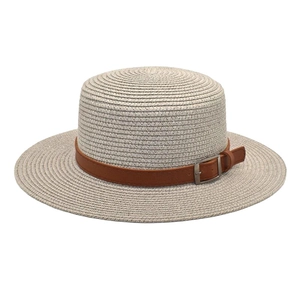 Vista detallada del sombrero boater de paja con copa plana y cinta marrón con hebilla