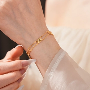 Close-up of vintage gold double-layer bracelet featuring hollow floral charms on model