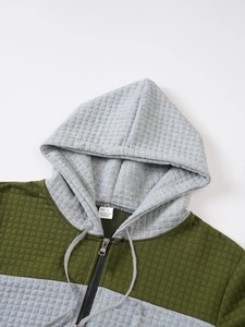 Detailed view of quilted grid pattern and washing label on green and gray hoodie