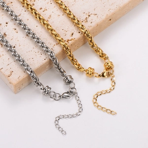 Close-up of 18k gold and silver woven circle chains on a beige textured stone base