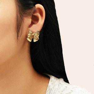Gros plan de boucles d'oreilles nœud doré avec texture métallique sur le profil d'un mannequin
