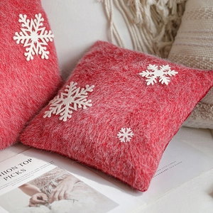 Red Christmas plush pillow with 3D snowflake decor on a cozy white sofa background