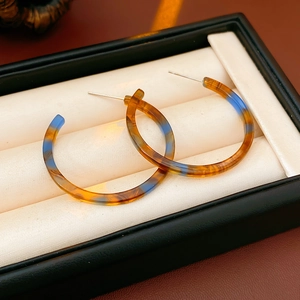Dettaglio di orecchini a cerchio in resina ambra e blu presentati in una scatola regalo