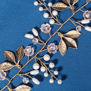 Golden bridal headband featuring white pearls and pink flowers on dark blue background