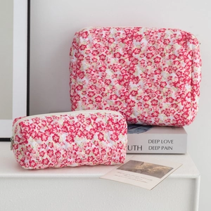 Detailed set of cherry blossom quilted makeup bags with silver zippers on a white desk