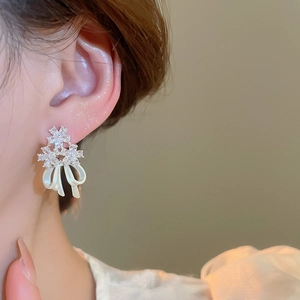 Close-up of 14k gold plated earrings featuring zircon flowers and pearl bow pendant