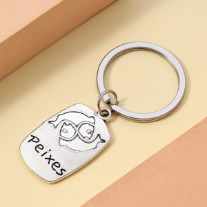Macro detail of silver Pisces zodiac keychain with engraved Peixes text on metal tag