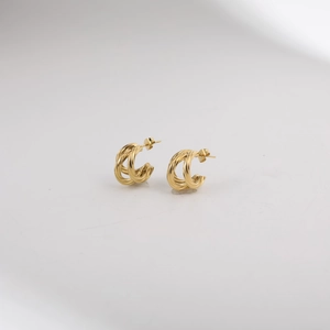 Detailed macro view of gold-plated twisted texture C-shape earrings with butterfly backings