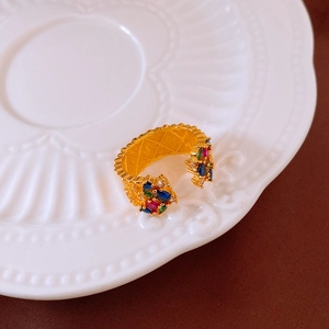 Detail shot of vintage gold ring with colorful zircon stones on white ceramic plate