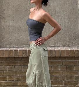 Detail of grey cropped tube top styled with olive cargo pants against brick wall