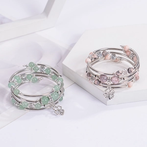 Close-up of pink zebra stone wrap bracelet with clover pendant and metal charms