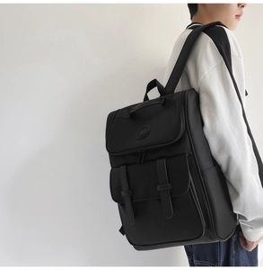 Side view of black nylon backpack featuring flap closure and dual buckle straps on model