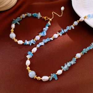Detailed macro of pearl and aquamarine beaded necklace set on elegant brown silk background