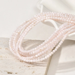 Close-up of 3mm natural freshwater shell round beads on minimalist stone and ceramic