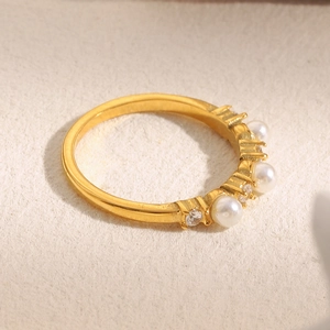 Detail shot of a gold ring with multiple white pearls and sparkling zircon stones