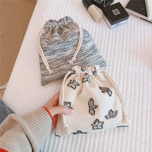 Close-up of minimalist cotton linen drawstring bags with floral embroidery and gray texture