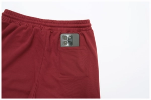 Detail of dark red sweatpants with elastic waist and deep back pocket for smartphone