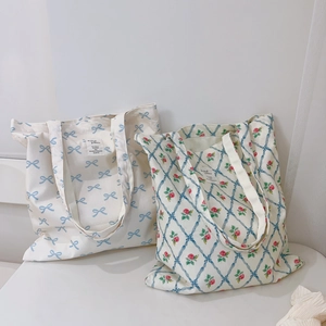 Floral canvas tote bags with blue bow prints and rose patterns in a minimalist style