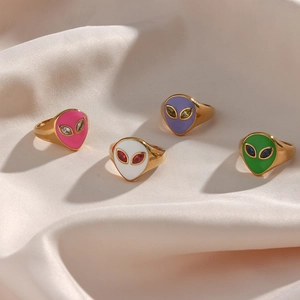 Golden alien head rings set with colorful enamel finish on elegant silk fabric