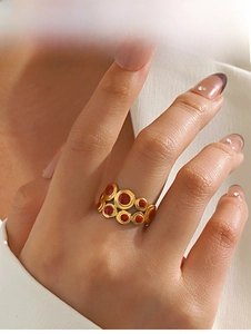 Macro shot of gold wide band ring with multiple red circular enamel inlays on fingers