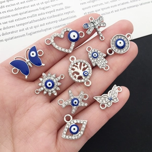 Detailed close-up of mixed Evil Eye charms for DIY jewelry making held in hand