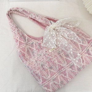 Close-up of pink floral tote bag with white lace embroidery and a large decorative bow