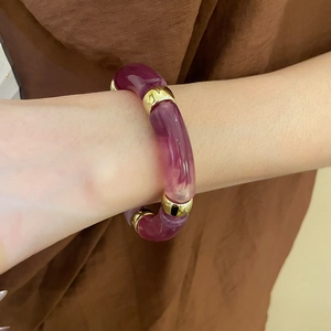 Detail of purple marble acrylic resin bracelet with gold metal links on a model's wrist