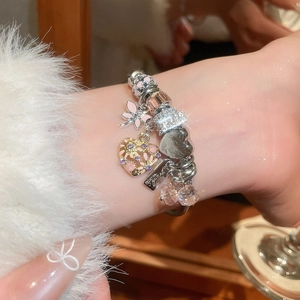 Detailed close-up of a silver charm bracelet with pink butterfly and crystal beads