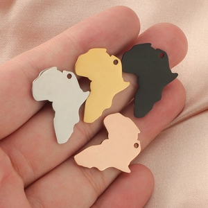 Detail of Africa map pendants in four metallic finishes held over pink silk fabric
