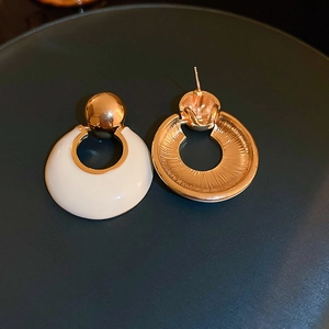 Detailed view of luxury gold round drop earrings with cream enamel finish and sunburst texture