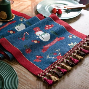 Blue Christmas table runner with snowman patterns and festive red fringe tassels