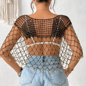 Détail d'un châle en maille crochet noire avec perles dorées et franges bohèmes au dos